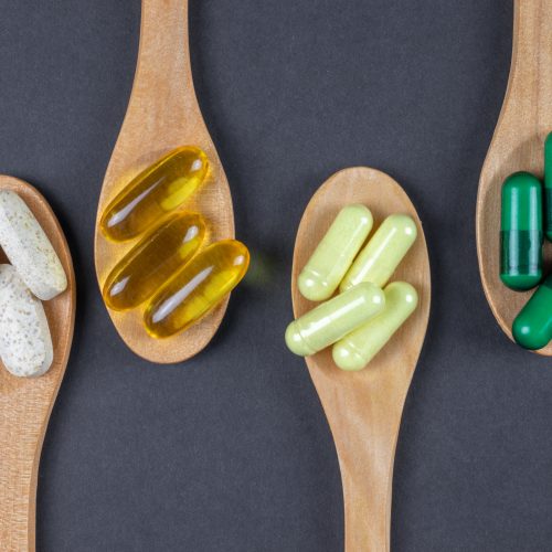 small wooden spoons with supplements, vitamins and pills